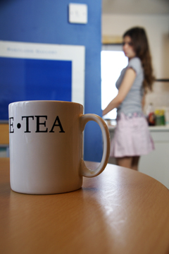 A mug of tea on a table with a girl in a short skirt in the background