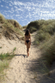 female in bikini walks into sand dunes