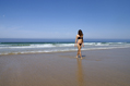 female in bikini walking out of the sea on a deserted beach