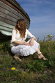 female in white lace sitting by a boat and looking away to far off
