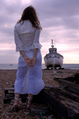 girl in white lace with fishing boat in background