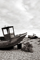 two old fishing boats leaning over on a shingle spit