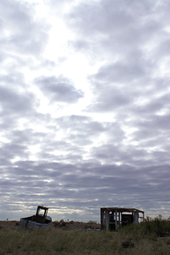 An old fishing boat and tumbled-down shack under a brooding sky