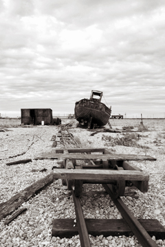 Old tracks leading to a boat and shack across a shingle spit