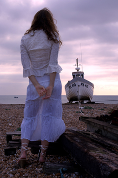 girl in white lace with fishing boat in background