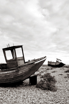 two old fishing boats leaning over on a shingle spit