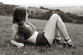 girl in crop top, hotpants and strappy sandals reclines in the grass