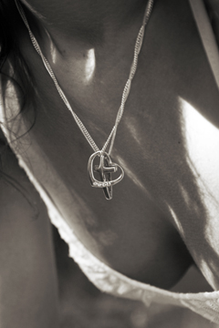 Cross and heart necklace entwined against womans breast