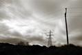 pylon power cables and telegraph wires crossing over against a stormy sky