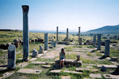 Girl sitting among ancient roman pillars in the desert